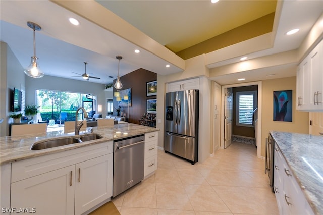 kitchen featuring pendant lighting, sink, appliances with stainless steel finishes, white cabinetry, and light stone countertops