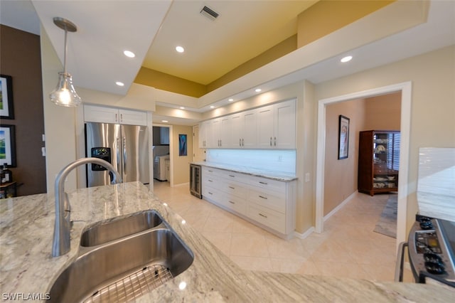 kitchen featuring stainless steel appliances, light stone countertops, sink, and white cabinets