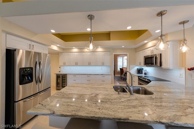 kitchen featuring decorative light fixtures, white cabinetry, kitchen peninsula, and stainless steel appliances