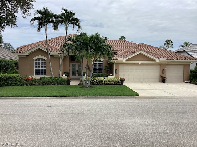 mediterranean / spanish home with a front lawn, a garage, and french doors