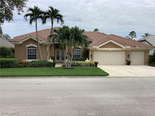 mediterranean / spanish-style home featuring a garage, french doors, and a front lawn