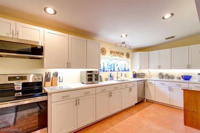 kitchen with appliances with stainless steel finishes, sink, light tile floors, and white cabinets