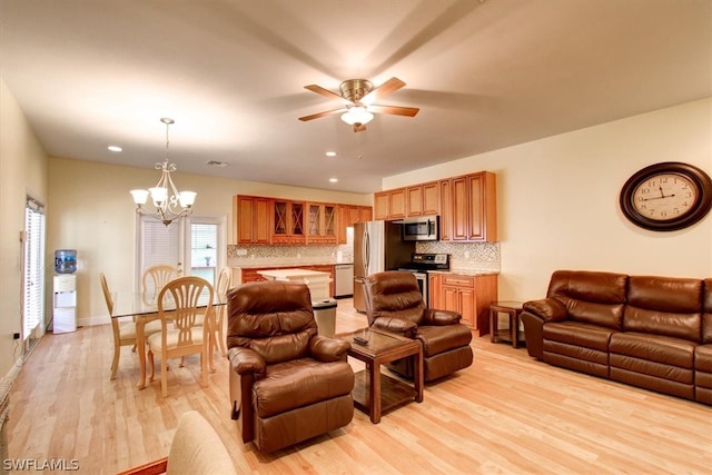 living room featuring light hardwood / wood-style floors and ceiling fan with notable chandelier