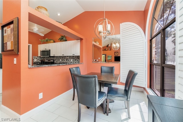 tiled dining room featuring high vaulted ceiling and ceiling fan with notable chandelier