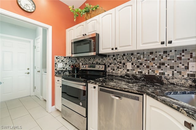 kitchen featuring appliances with stainless steel finishes, tasteful backsplash, dark stone countertops, white cabinets, and light tile floors