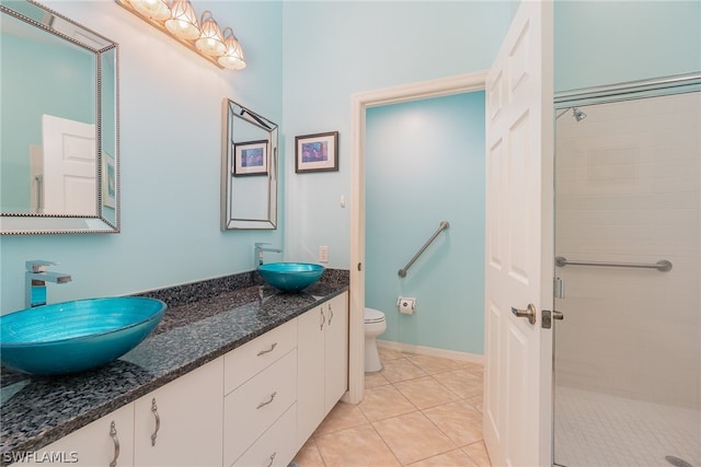 bathroom with tiled shower, toilet, tile floors, and dual vanity