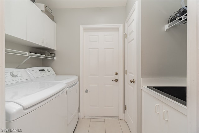 washroom featuring washing machine and dryer, cabinets, and light tile floors