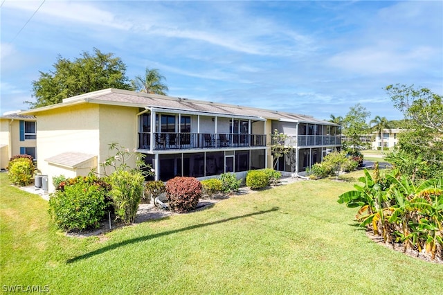 rear view of house featuring a sunroom, a lawn, and central AC