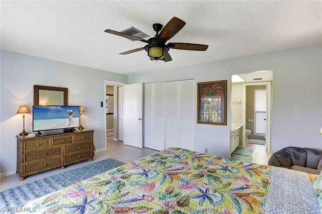 tiled bedroom with ceiling fan, a textured ceiling, a closet, and connected bathroom