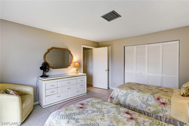 bedroom featuring a closet, light tile patterned floors, and a textured ceiling