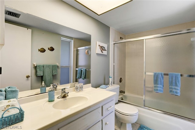 full bathroom with vanity, bath / shower combo with glass door, and toilet