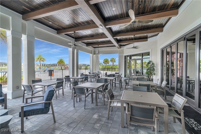 view of patio / terrace featuring a water view, fence, a ceiling fan, and outdoor dining space
