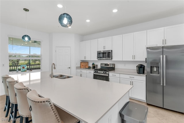 kitchen featuring appliances with stainless steel finishes, a sink, light countertops, white cabinetry, and a center island with sink