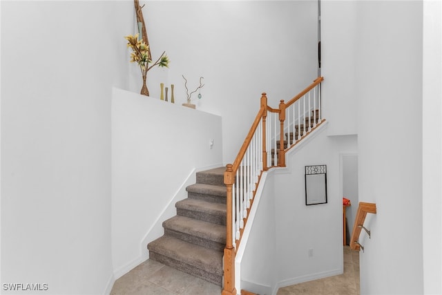 stairs with baseboards and a high ceiling
