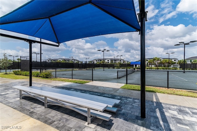 view of community with a tennis court and fence