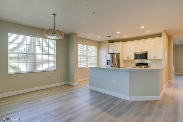 kitchen featuring hanging light fixtures, light hardwood / wood-style floors, white cabinetry, and stainless steel appliances