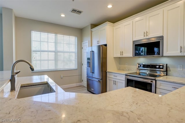 kitchen featuring sink, stainless steel appliances, light stone countertops, and white cabinetry