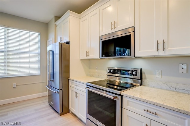 kitchen with light wood-type flooring, stainless steel appliances, white cabinetry, and light stone countertops