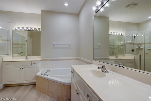 bathroom featuring hardwood / wood-style floors, separate shower and tub, and dual vanity