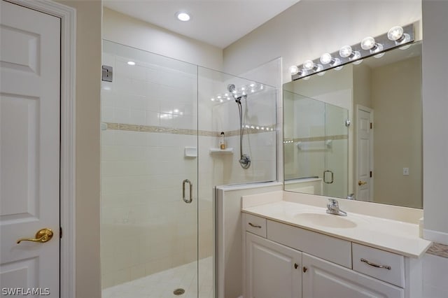 bathroom featuring a shower with door and vanity