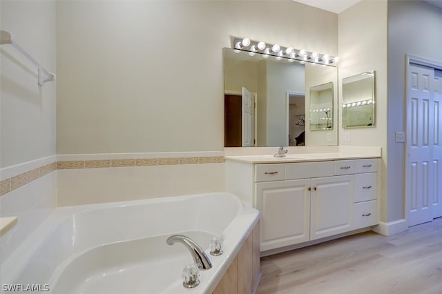 bathroom featuring hardwood / wood-style floors, vanity, and a relaxing tiled bath