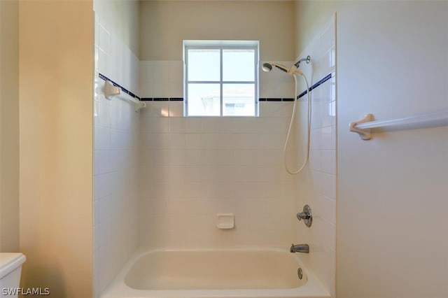 bathroom featuring toilet and tiled shower / bath