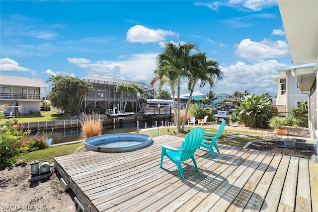 wooden deck featuring a water view, a dock, and an outdoor hot tub