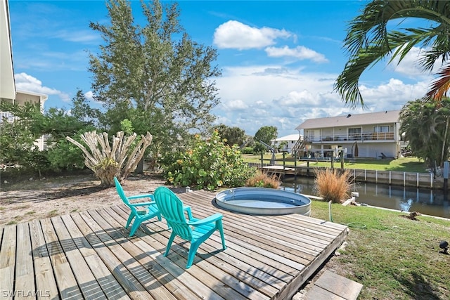 deck with a water view, a hot tub, and a lawn