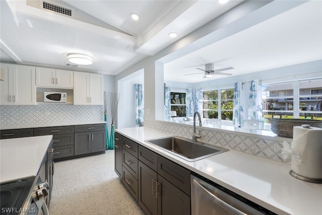 kitchen with lofted ceiling, decorative backsplash, white cabinets, appliances with stainless steel finishes, and sink