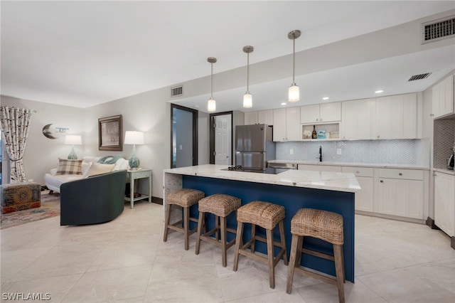 kitchen featuring white cabinets, stainless steel fridge, tasteful backsplash, and light stone countertops