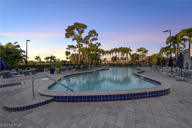 pool at dusk with a patio area