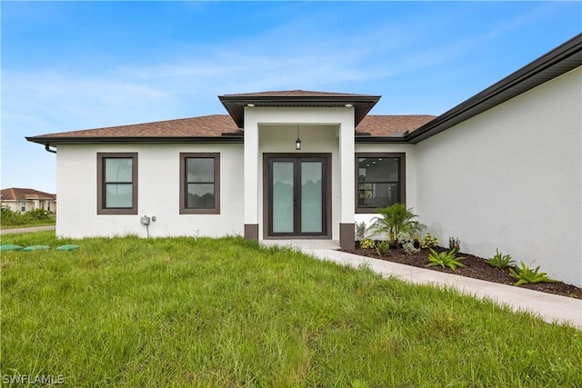 back of house with french doors and a lawn