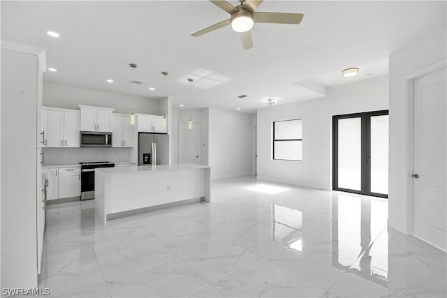 kitchen with stainless steel appliances, ceiling fan, pendant lighting, white cabinets, and a kitchen island