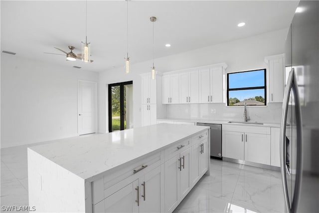 kitchen featuring appliances with stainless steel finishes, sink, decorative light fixtures, a center island, and white cabinetry