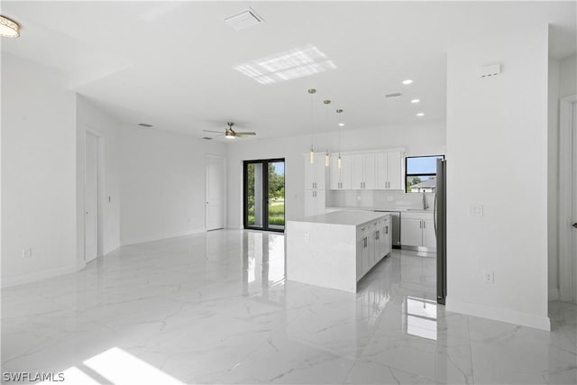 kitchen featuring ceiling fan, a center island, hanging light fixtures, stainless steel dishwasher, and white cabinets