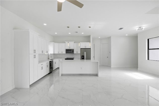 kitchen with decorative light fixtures, a center island, white cabinetry, and stainless steel appliances