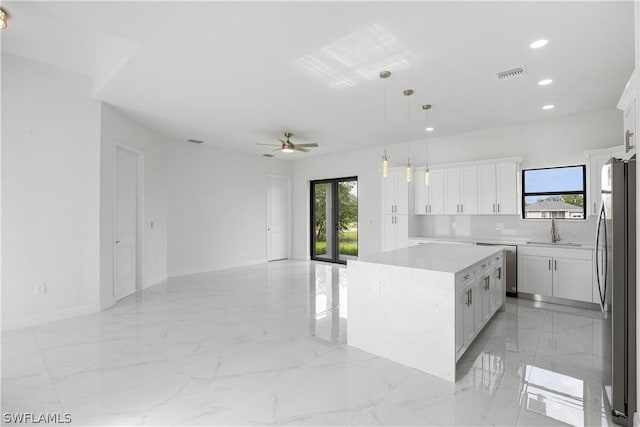 kitchen with a center island, white cabinets, hanging light fixtures, ceiling fan, and appliances with stainless steel finishes