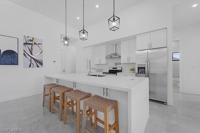 kitchen featuring appliances with stainless steel finishes, wall chimney range hood, decorative light fixtures, and light tile floors