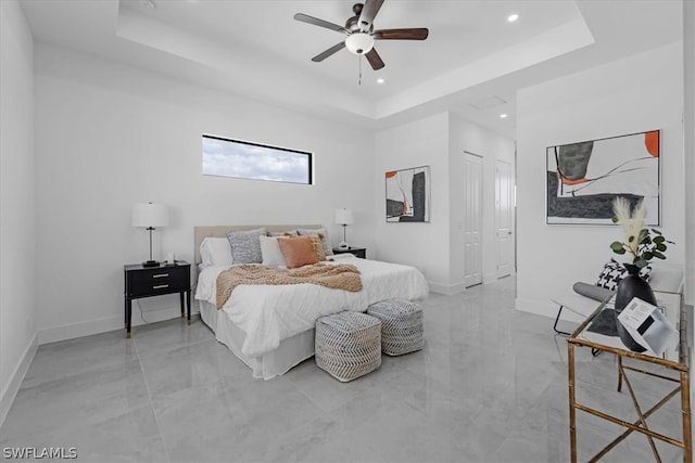 bedroom featuring a closet, ceiling fan, a tray ceiling, and tile flooring