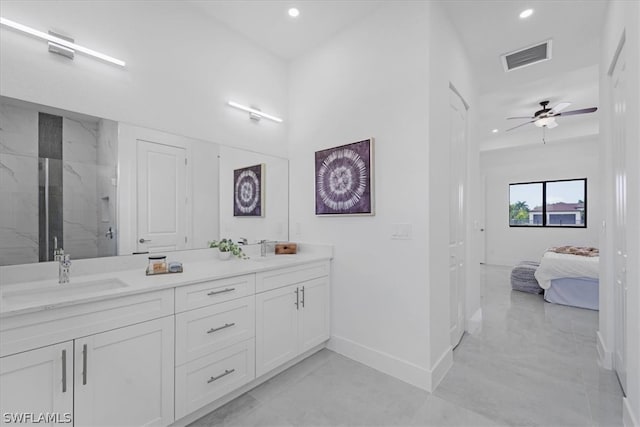 bathroom featuring tiled shower, ceiling fan, dual sinks, oversized vanity, and tile floors