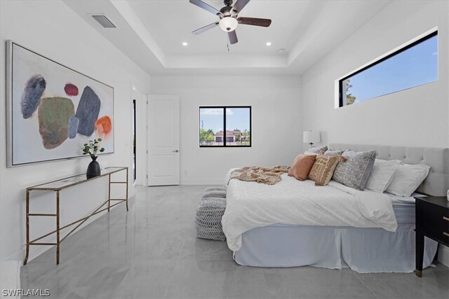 tiled bedroom featuring ceiling fan and a tray ceiling