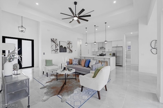 tiled living room with french doors, ceiling fan, a high ceiling, and a tray ceiling