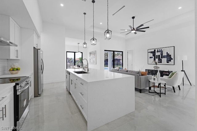 kitchen with appliances with stainless steel finishes, a center island with sink, white cabinets, sink, and pendant lighting