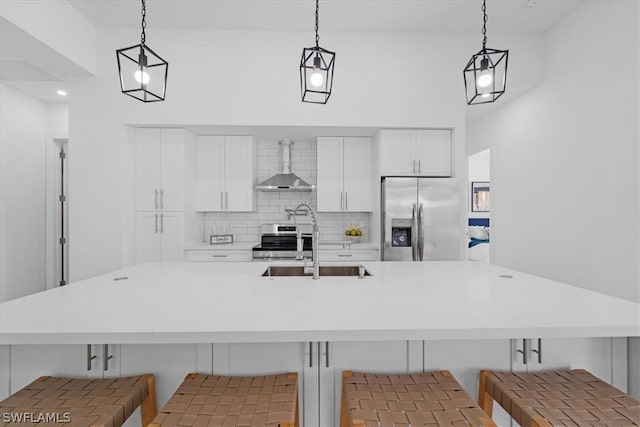 kitchen featuring hanging light fixtures, backsplash, stainless steel fridge, and wall chimney exhaust hood