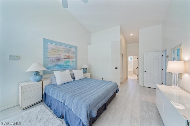 bedroom featuring connected bathroom, ceiling fan, high vaulted ceiling, and light wood-type flooring