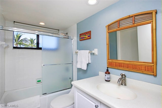 full bathroom with large vanity, toilet, and bath / shower combo with glass door