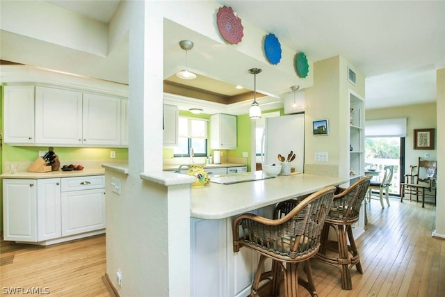 kitchen featuring decorative light fixtures, a kitchen bar, light hardwood / wood-style floors, and a wealth of natural light