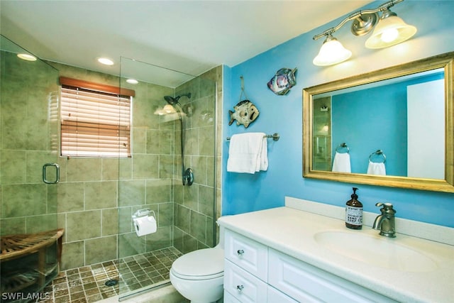 bathroom with a shower with door, vanity, and toilet