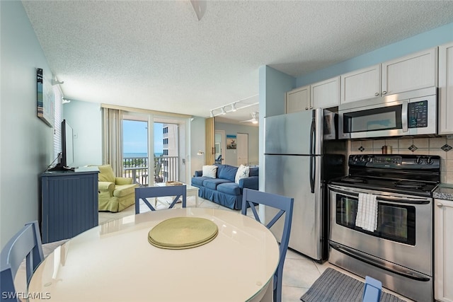 kitchen with range, rail lighting, a textured ceiling, fridge, and decorative backsplash