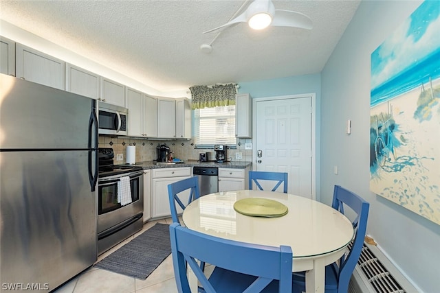 kitchen featuring stainless steel appliances, light tile patterned floors, decorative backsplash, a textured ceiling, and ceiling fan